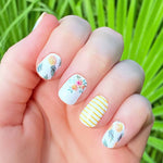 White nail wraps overlayed with a combination of pineapples, yellow flowers and yellow stripe overlays nail wrap nail design