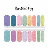 A mix of pastel solids covered with black speckled dots nail wrap nail design.