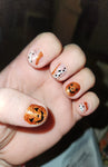 jack-o-lantern Halloween accent nails with orange glitter and white curvy lines on clear