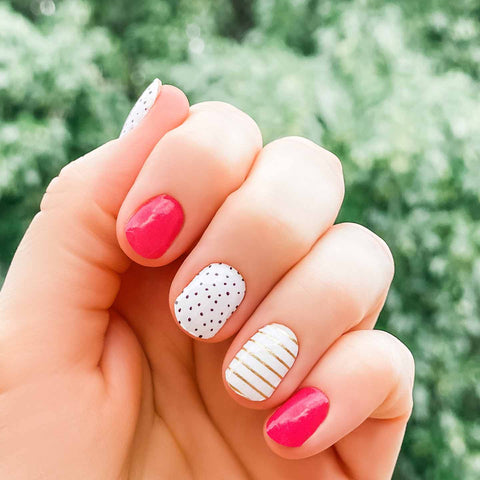 A combination of solid red, gold glitter stripes on white and black spots on white  nail wrap nail design.  