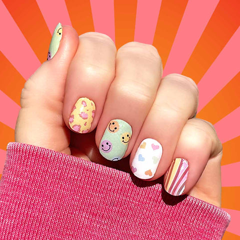 Combination of multicolored smiley faces on a light green background, pink leopard spots on a light yellow background, pastel hearts on a white background, and pastel rainbow curves nail wrap nail design.  